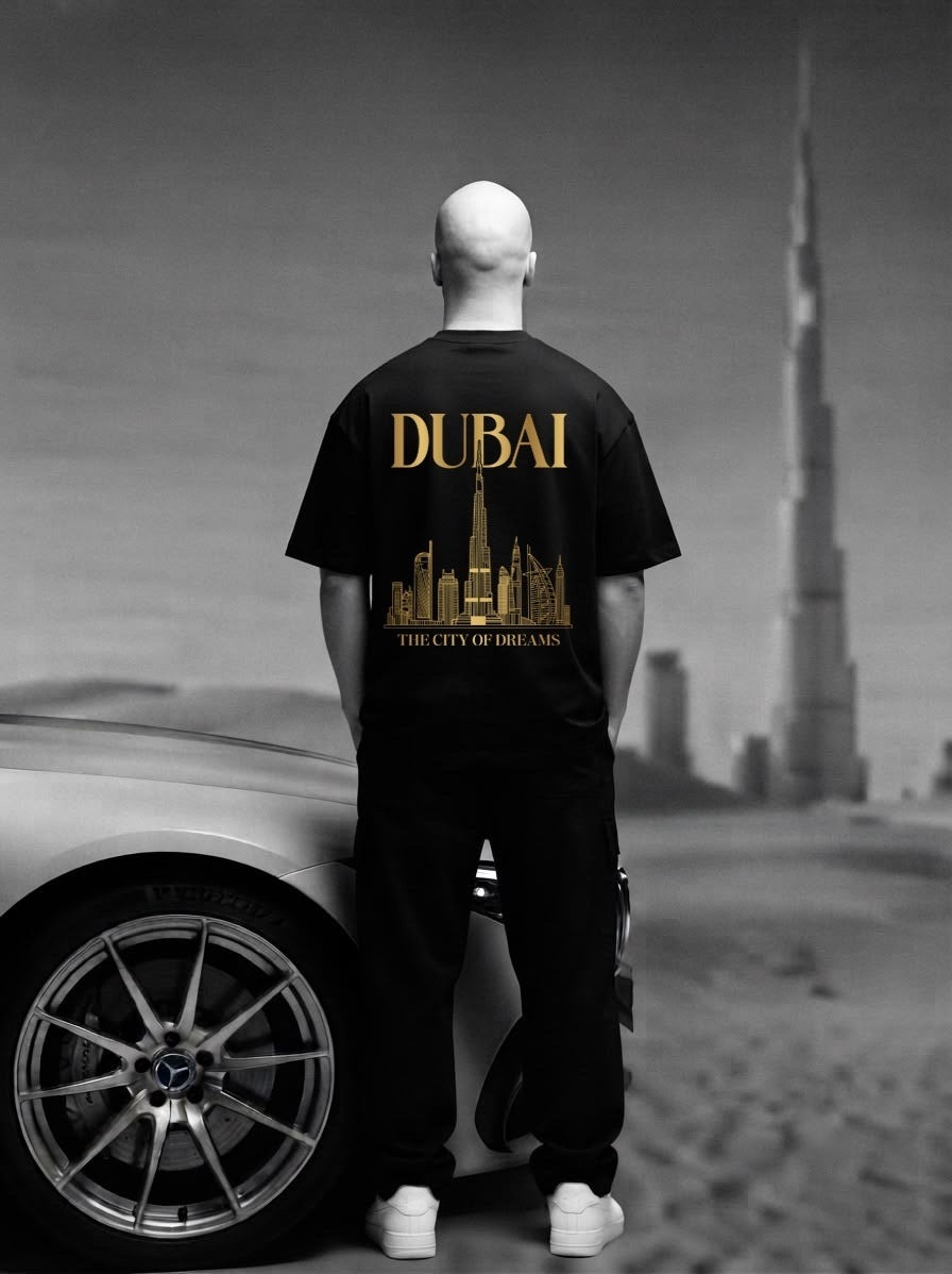 Man facing the Burj Khalifa in the black City of Dreams oversized tee, back print