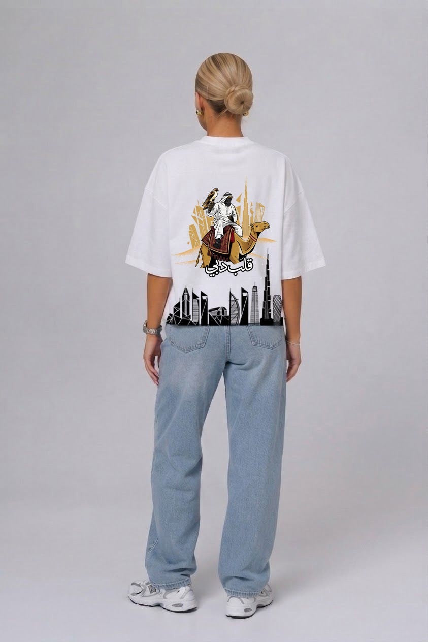 Woman showing the falconer and Dubai skyline back print on the white Dubai's Heart oversized tee